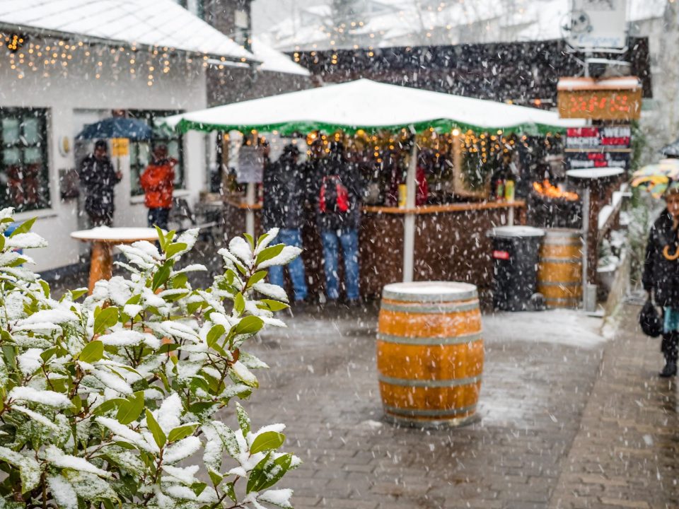 Glühweinstand mit Weinfässern im Schneetreiben beim Mosel-Wein-Nachts-Markt